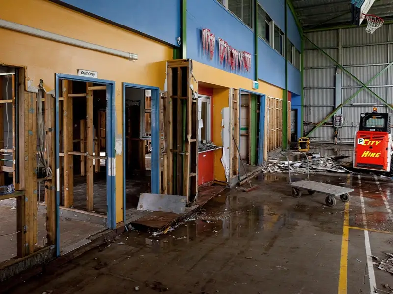 Damaged gym interior with exposed walls and debris.