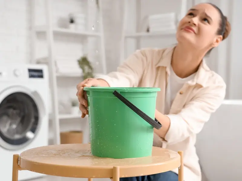 Woman holding a green bucket in a laundry room.